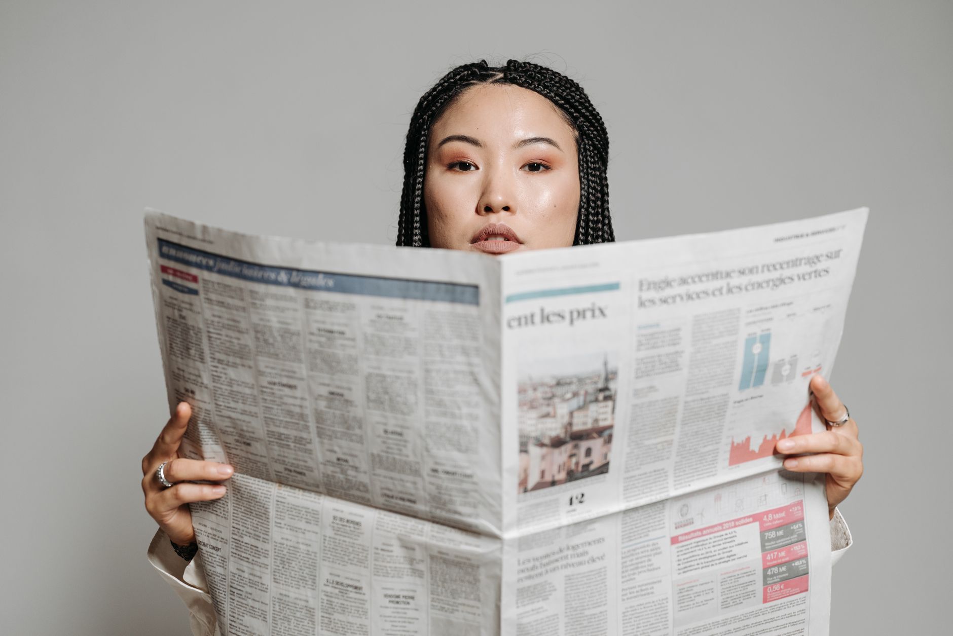 Woman holding and reading a physical newspaper newspaper closely